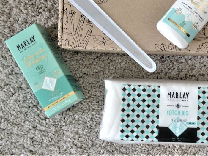 Le coton bio, la lotion et la lime Marlay posés sur un tapis clair